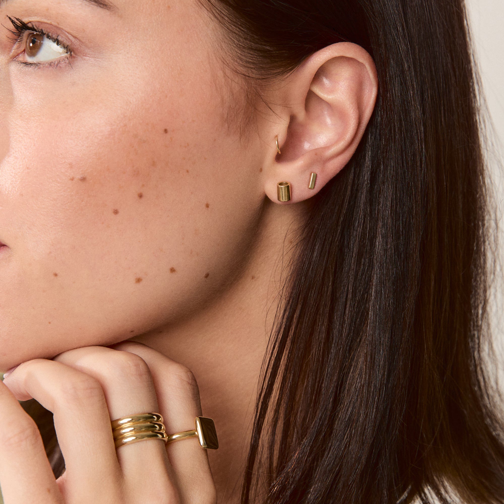 14k solid gold jewelry on model showcasing the perfect earring stack with tube studs and bar studs.