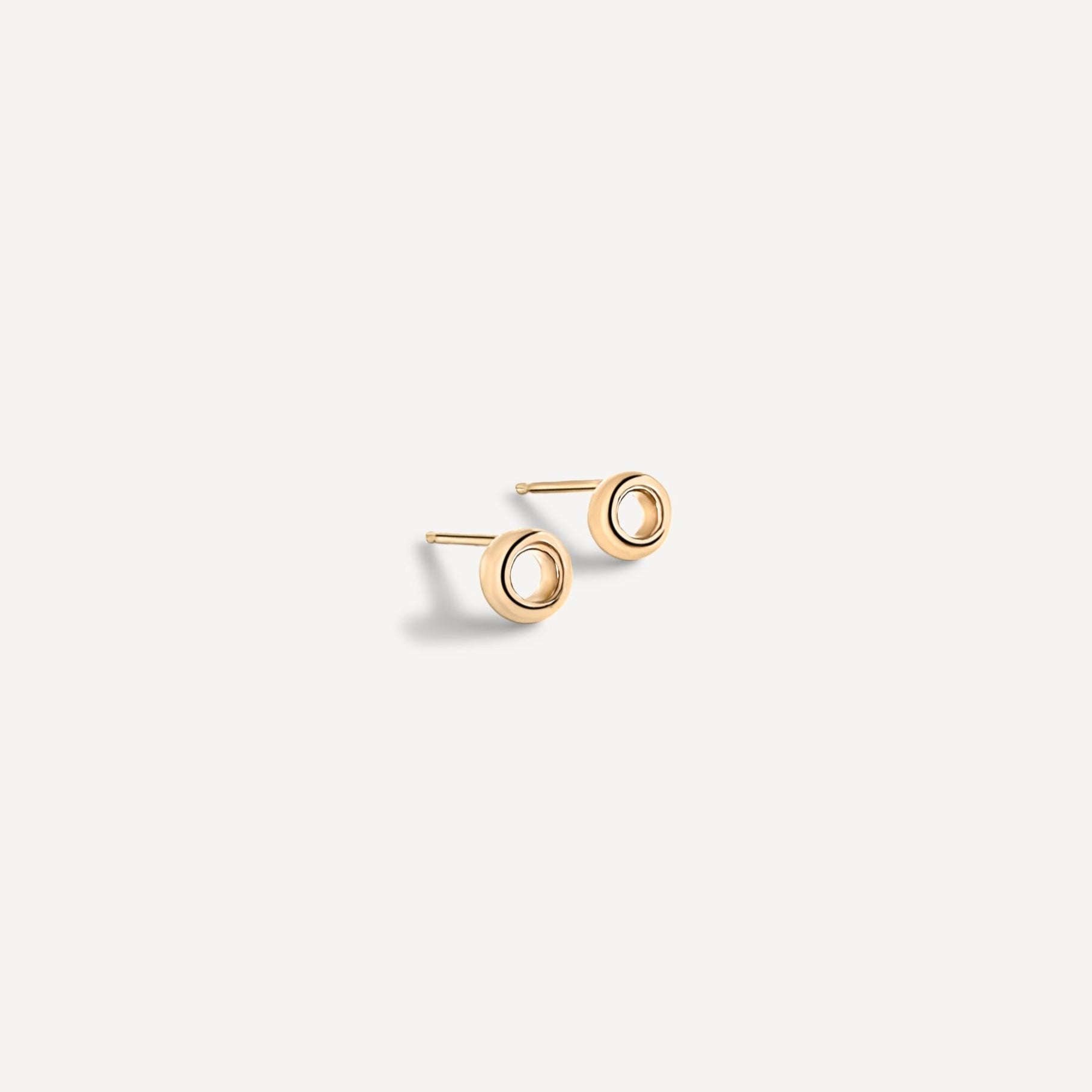Solid gold open circle studs shown from side angle, highlighting the precise craftsmanship and hollow center detail
