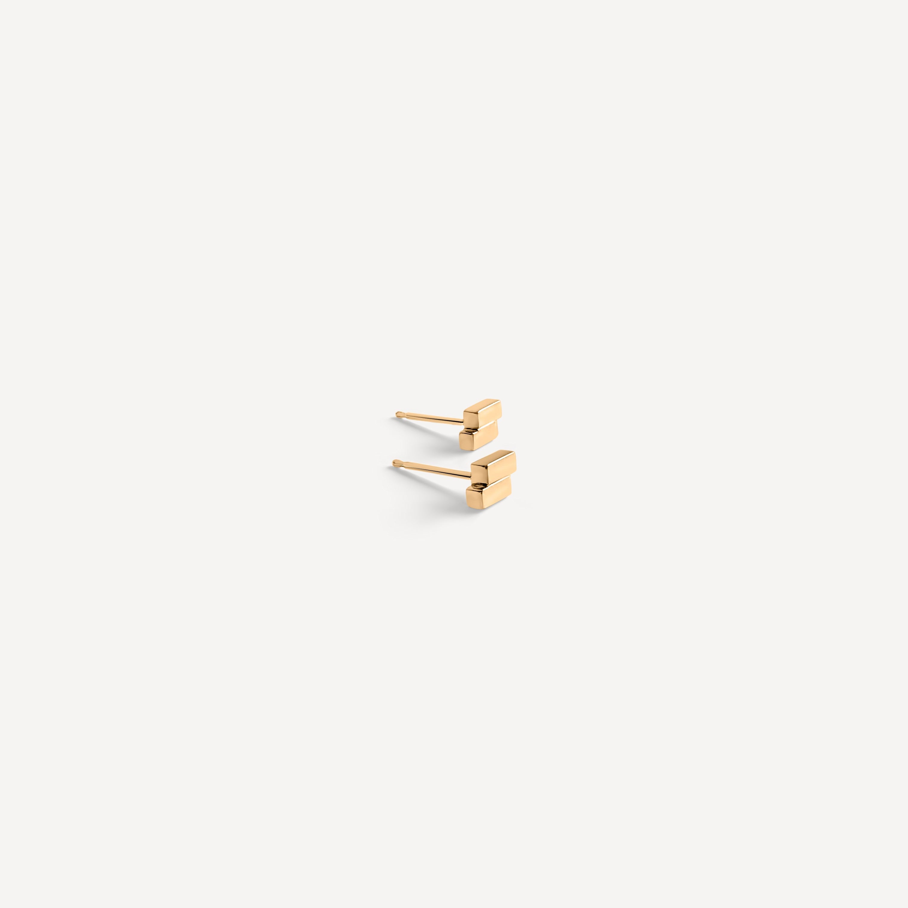 Minimal solid gold bar studs shown from side angle, featuring architectural rectangular design for modern minimalist style.