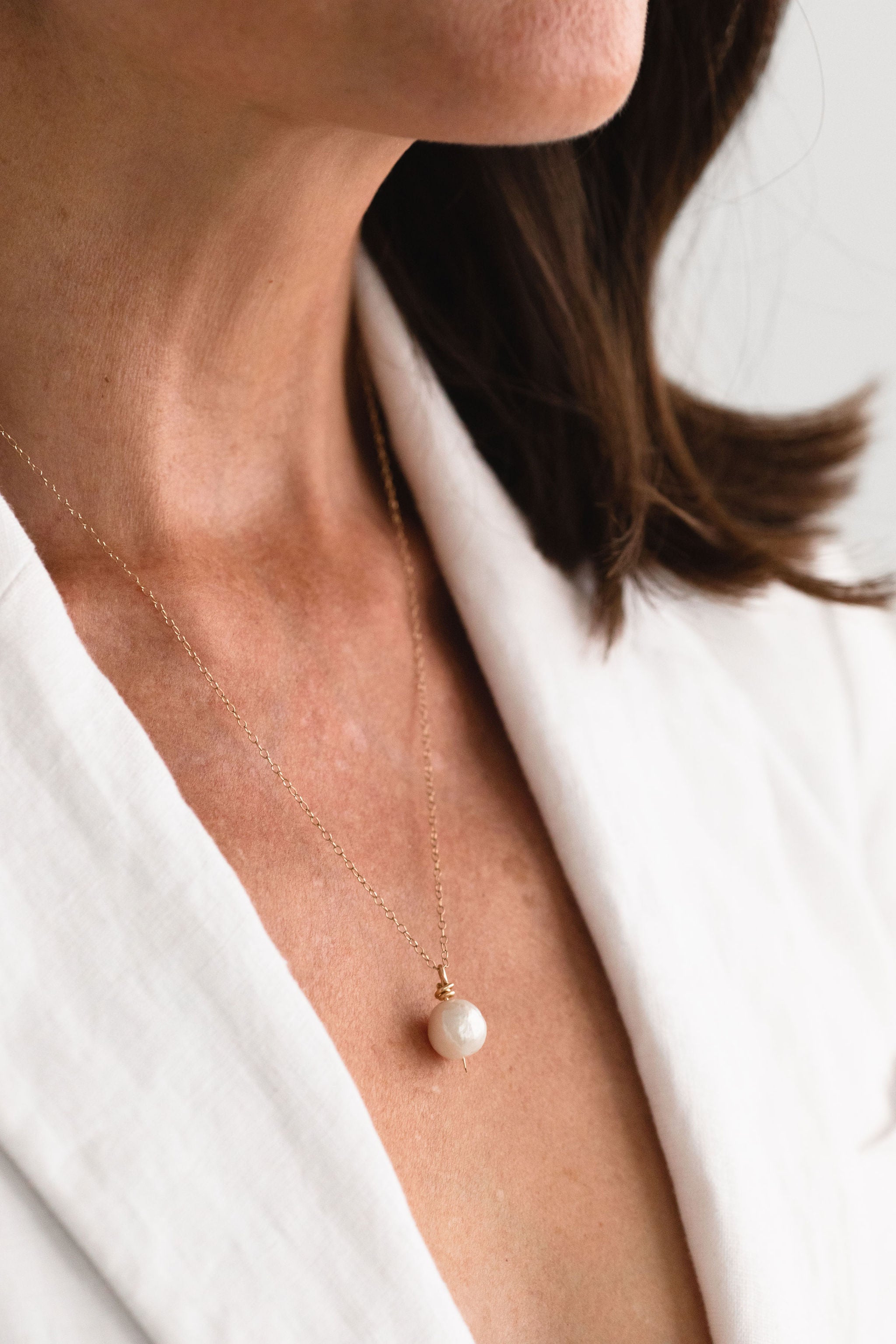 Model wearing a handcrafted Baroque Pearl Necklace by Sheena Marshall Jewelry, featuring a unique 9-13mm Baroque pearl and a 14k gold-filled chain, perfectly complementing an elegant outfit with its organic beauty.