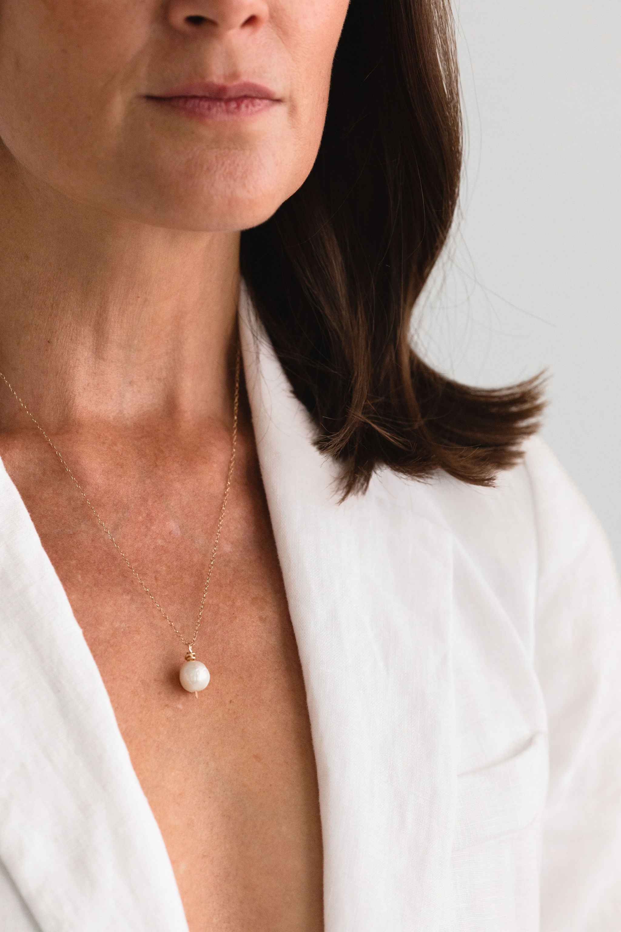 Model wearing a handcrafted Baroque Pearl Necklace by Sheena Marshall Jewelry, featuring a unique 9-13mm Baroque pearl and a 14k gold-filled chain, perfectly complementing an elegant outfit with its organic beauty.