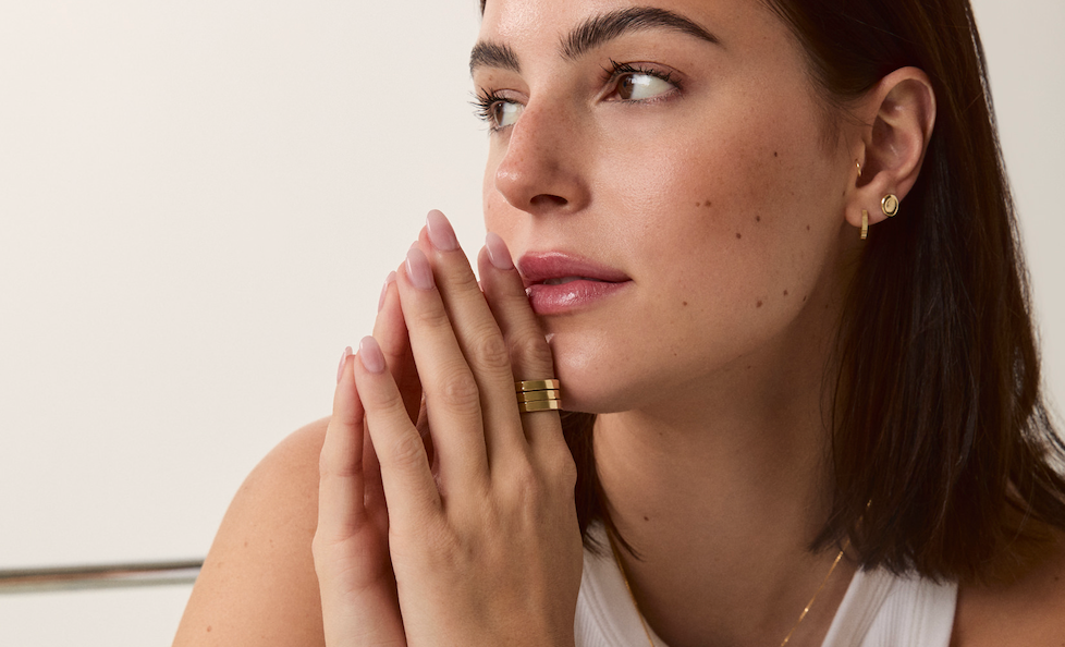 Model wearing stacked gold rings and minimalist gold earrings by Sheena Marshall Jewelry, showcasing elegant and timeless style
