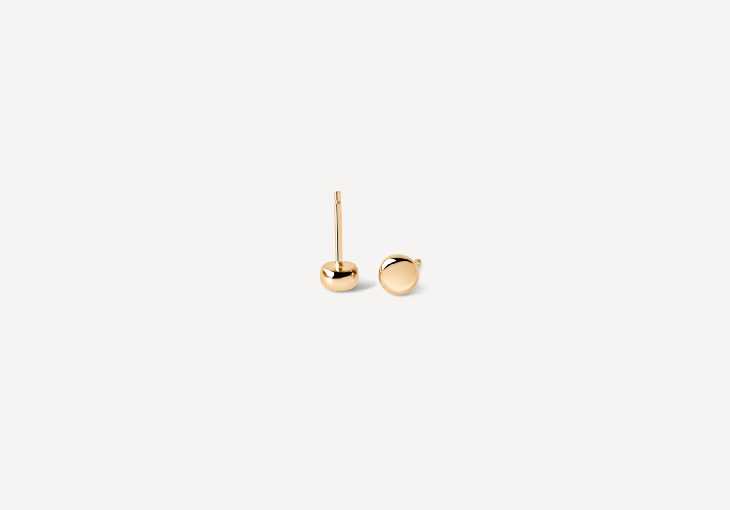 Simple gold seed studs at angle, displaying perfect sphere design for minimalist jewelry lovers seeking timeless pieces
