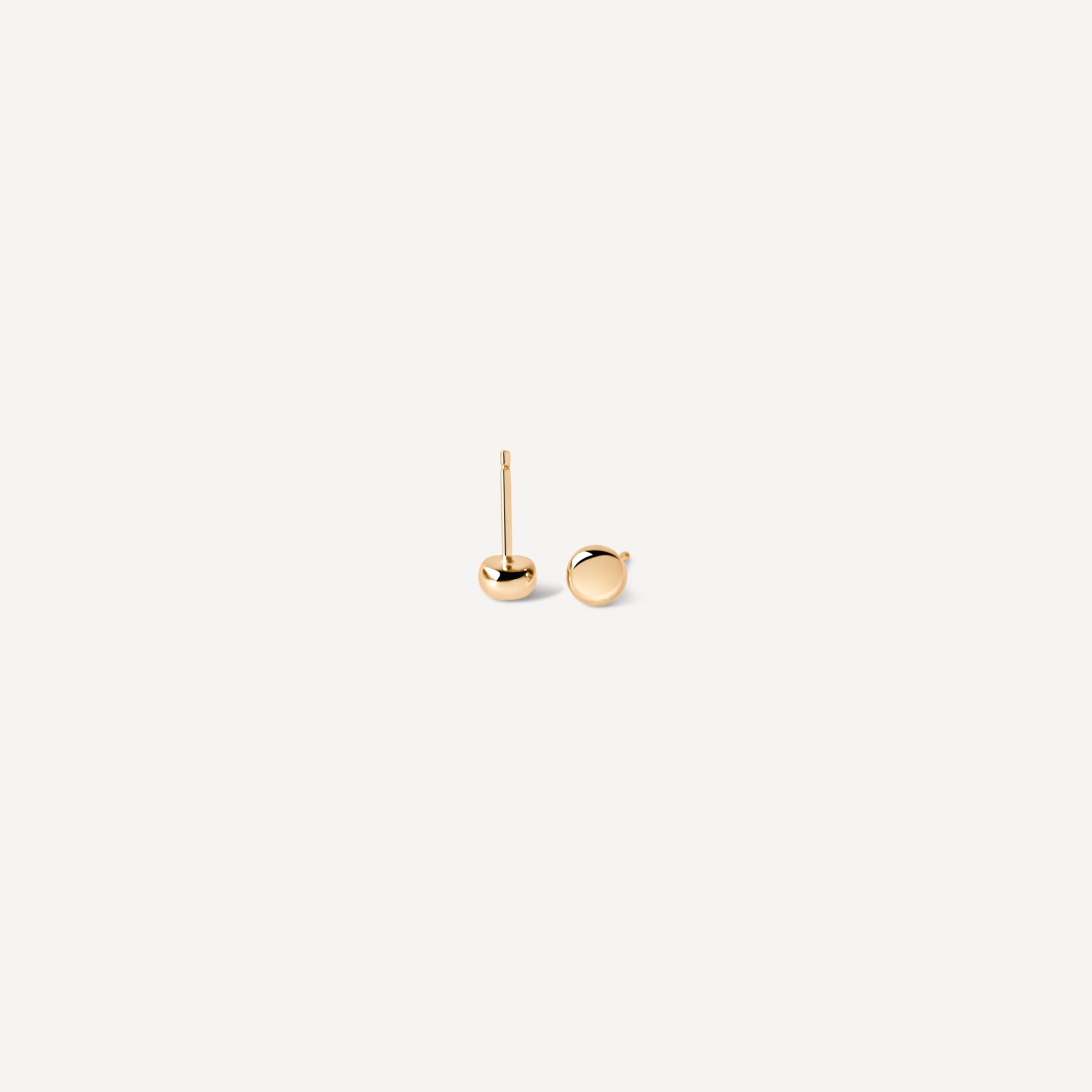 Simple gold seed studs at angle, displaying perfect sphere design for minimalist jewelry lovers seeking timeless pieces