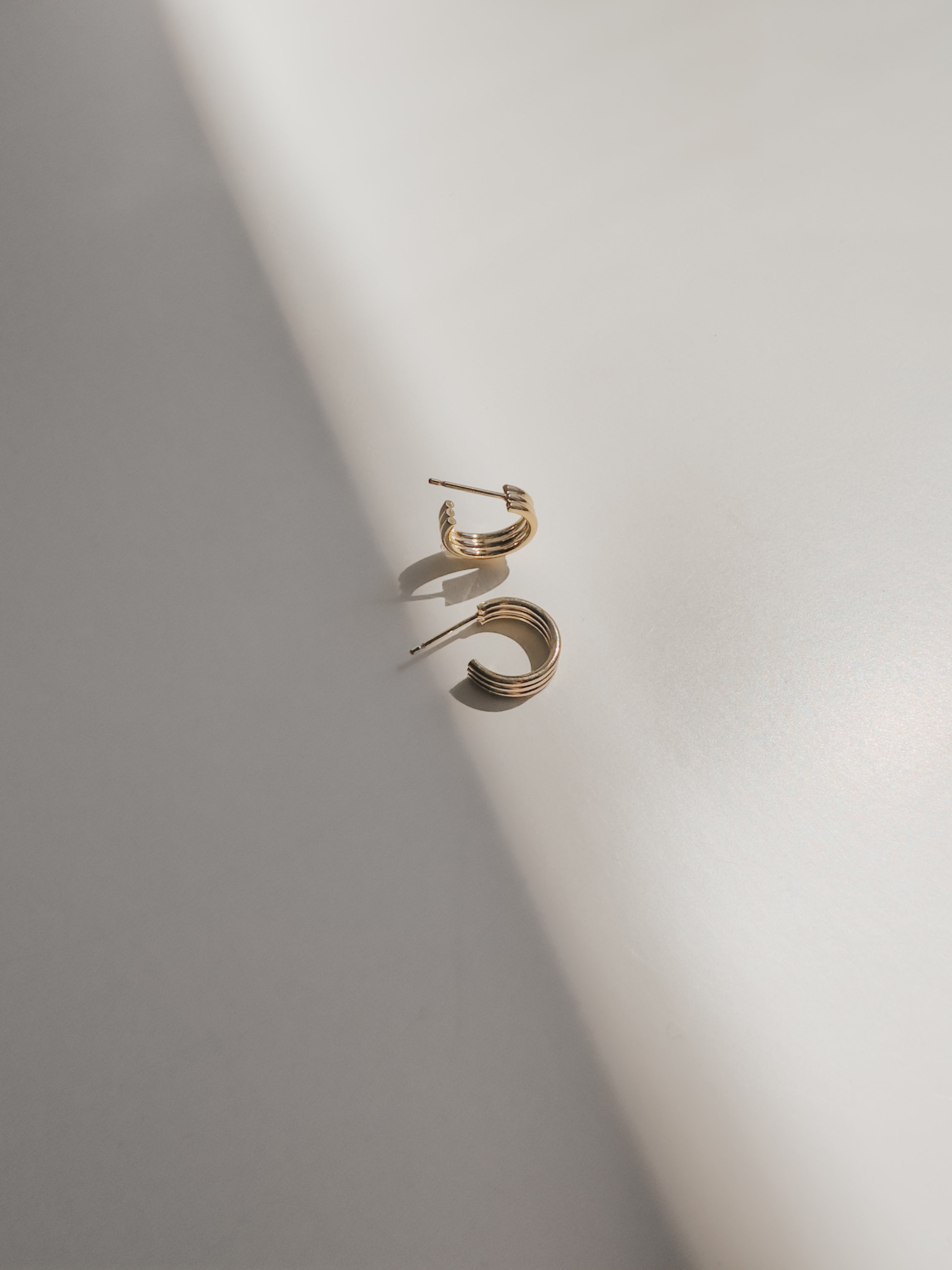 Closeup of Triple Hoop Earrings, highlighting their interwoven design and golden sheen.