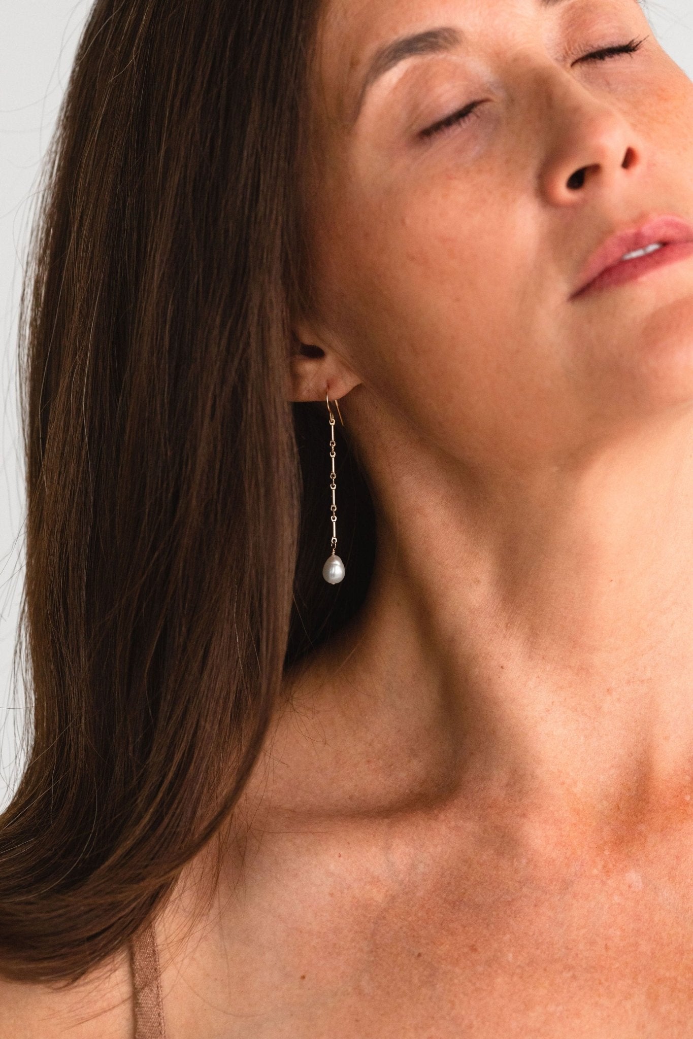 Close-up of woman wearing Florentine Earrings with freshwater pearls.