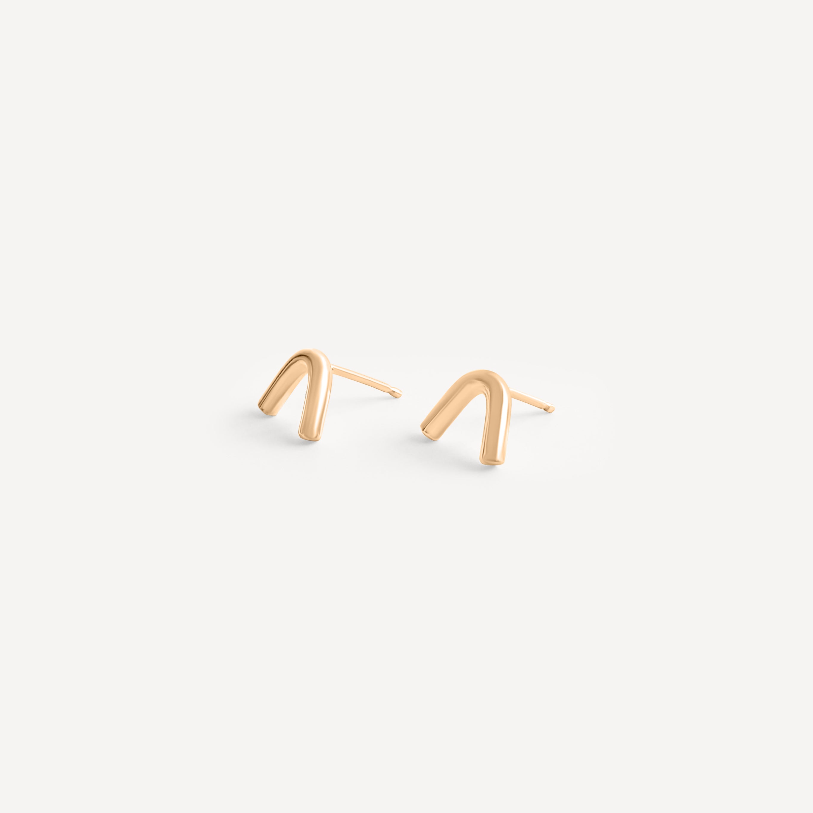 Handcrafted 14k gold arch stud earrings by Sheena Marshall Jewelry, measuring 7mm in height and 8.5mm in width, featuring an architectural design for refined casual elegance and heirloom quality.