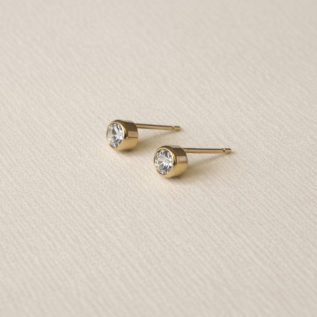 Bezel Gold  Fill stud earrings on a beige textured background