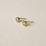 Bezel Gold  Fill stud earrings on a beige textured background