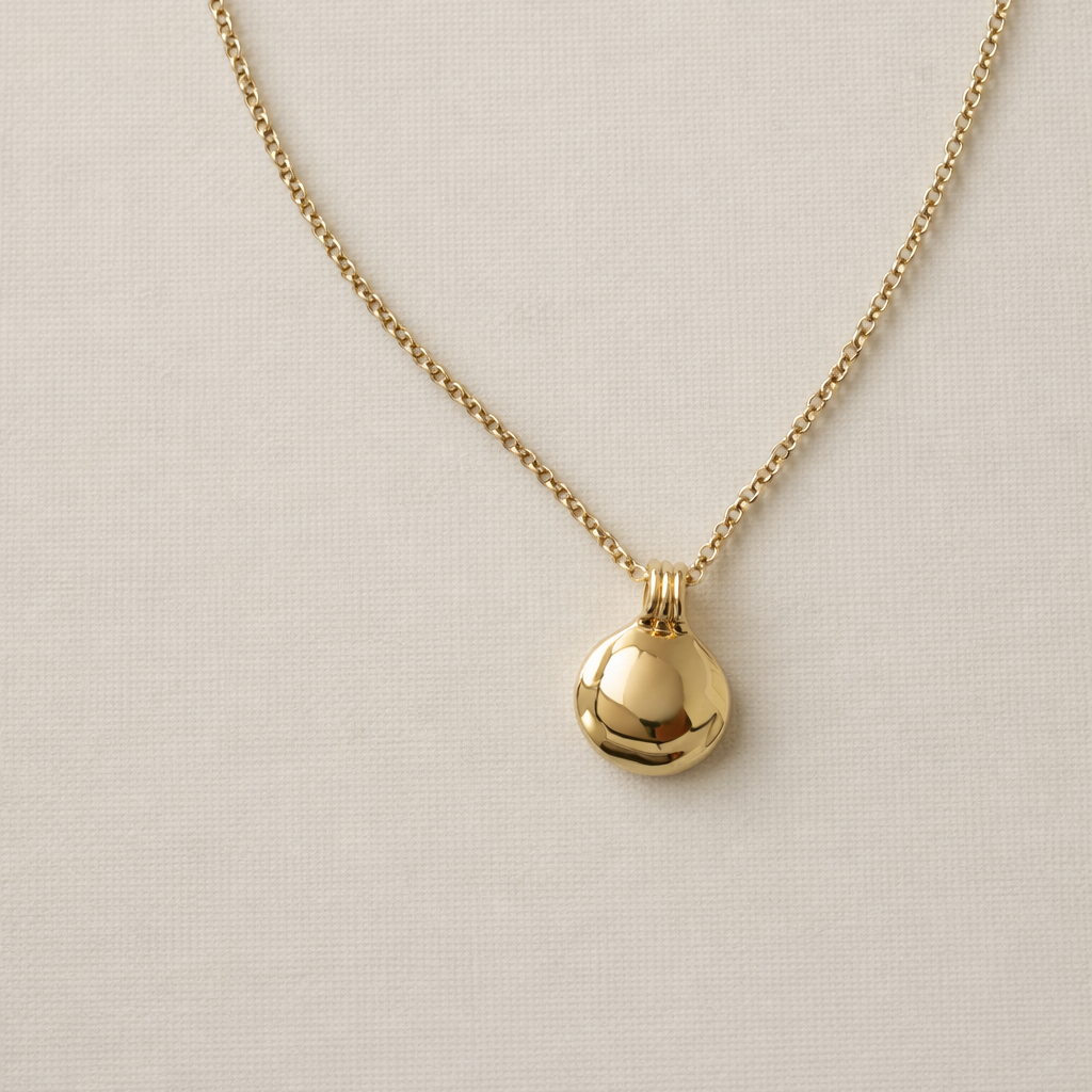 Gold necklace with a small pendant on a beige background