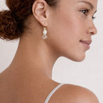 Close-up of a woman wearing pearl earrings with a neutral background