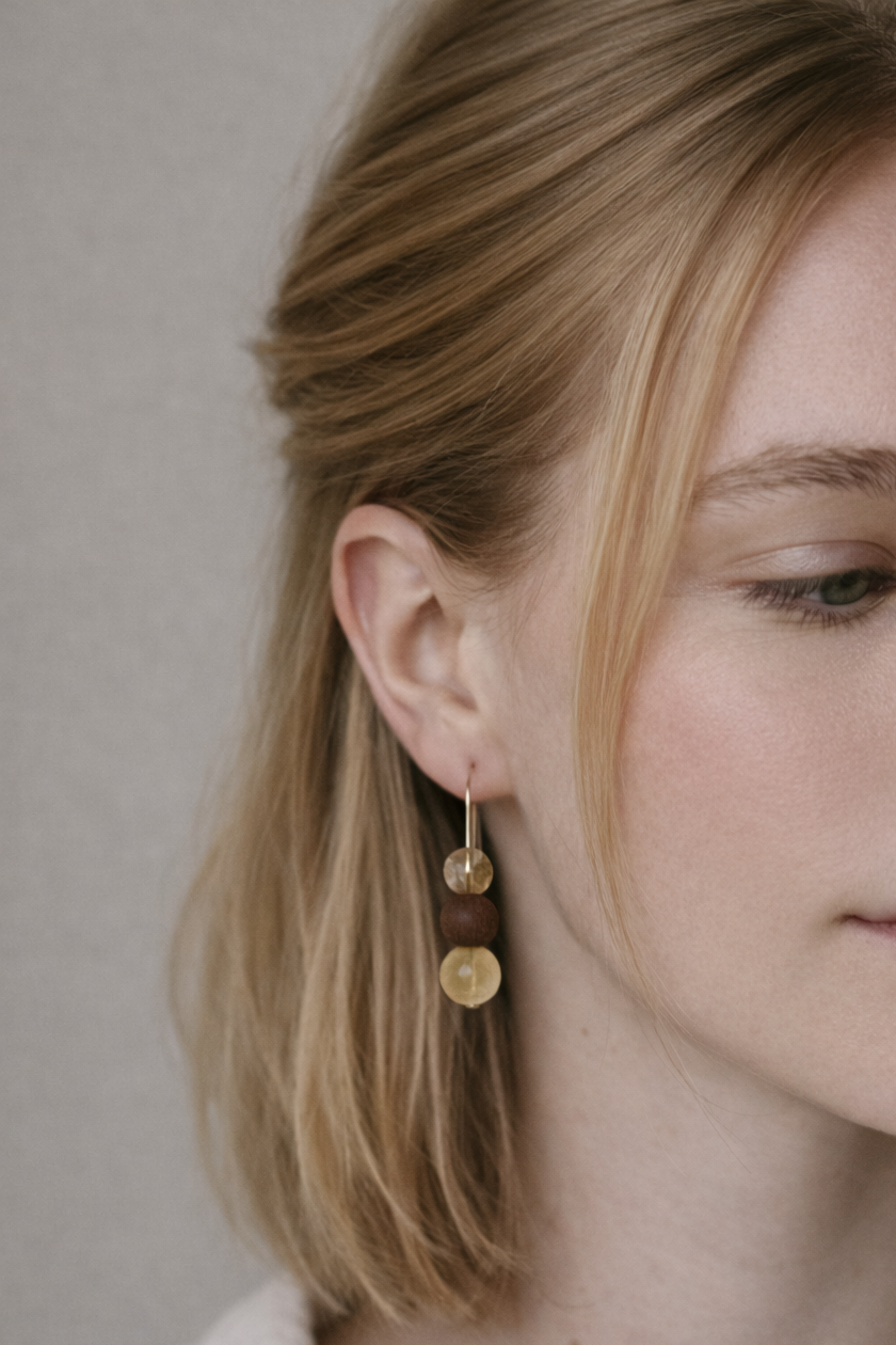 Close-up of a woman wearing gold earrings with a neutral background