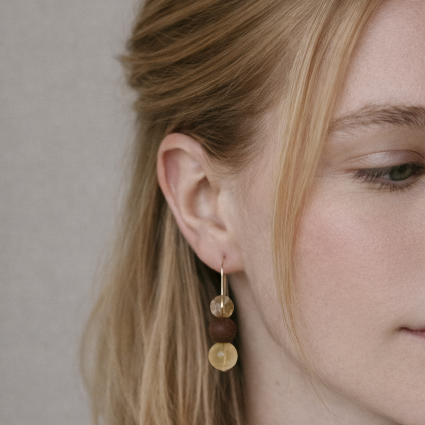 Close-up of a woman wearing gold earrings with a neutral background