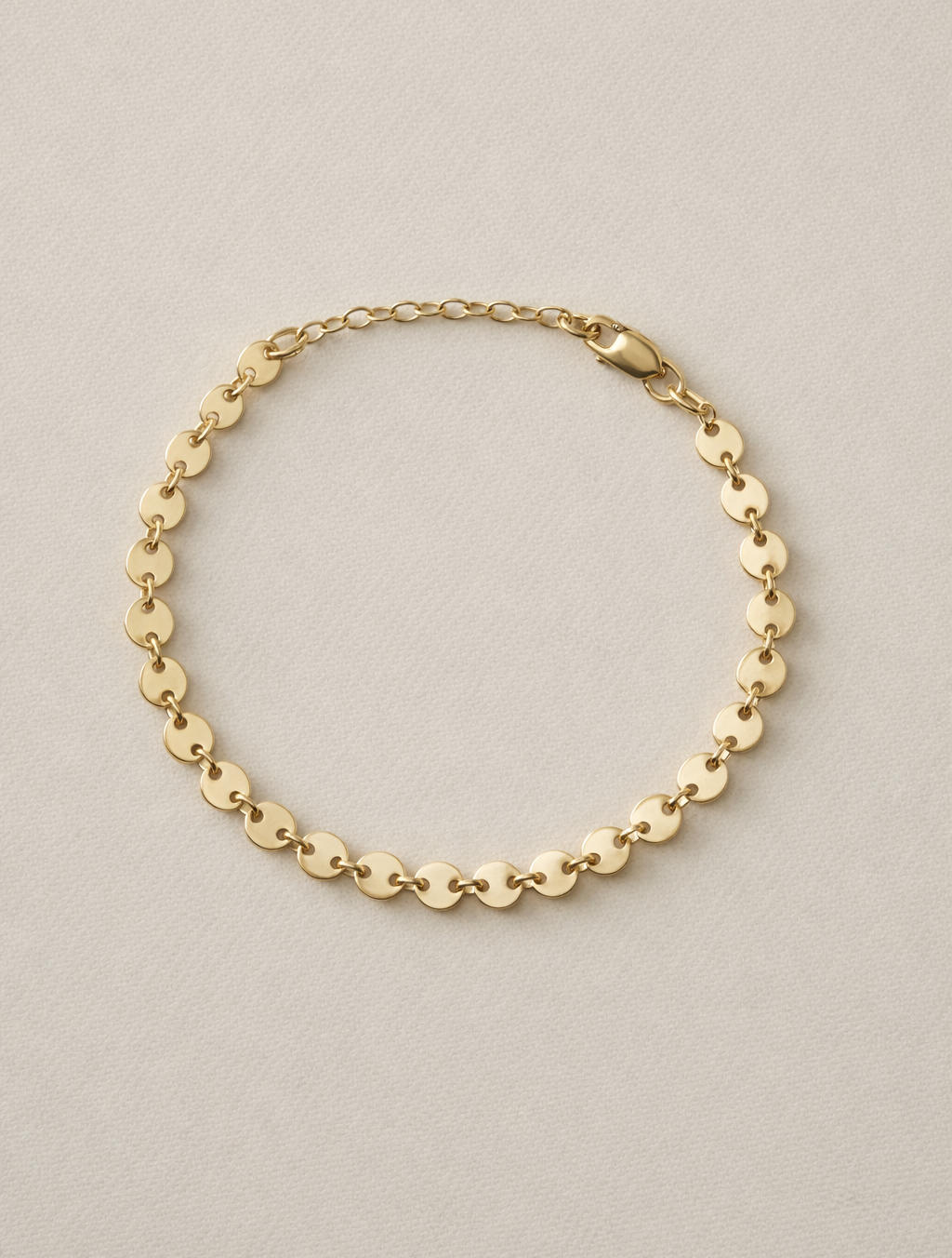Confettie Disc Gold chain bracelet on a beige background with one inch extender