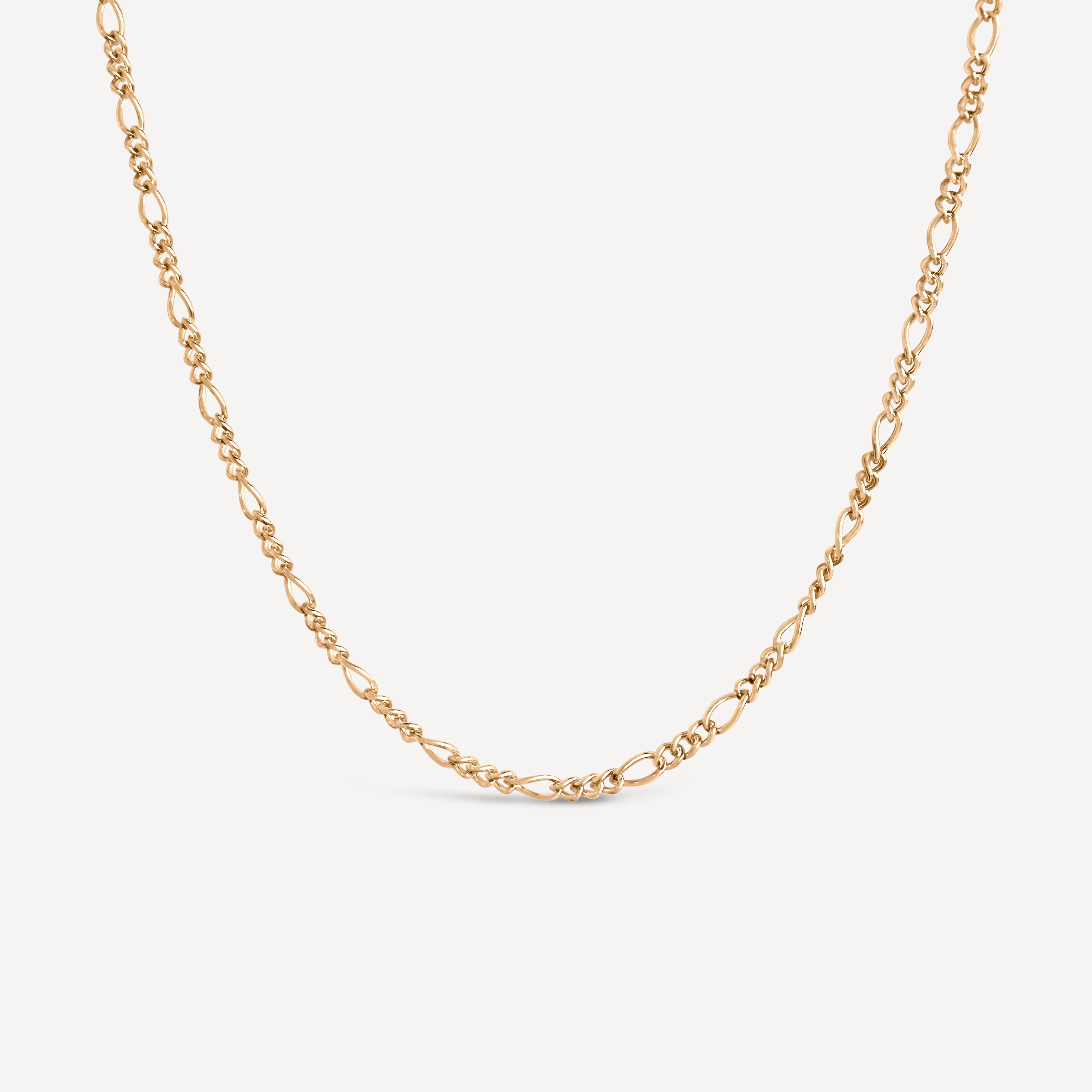 Gold chain necklace on a light beige background