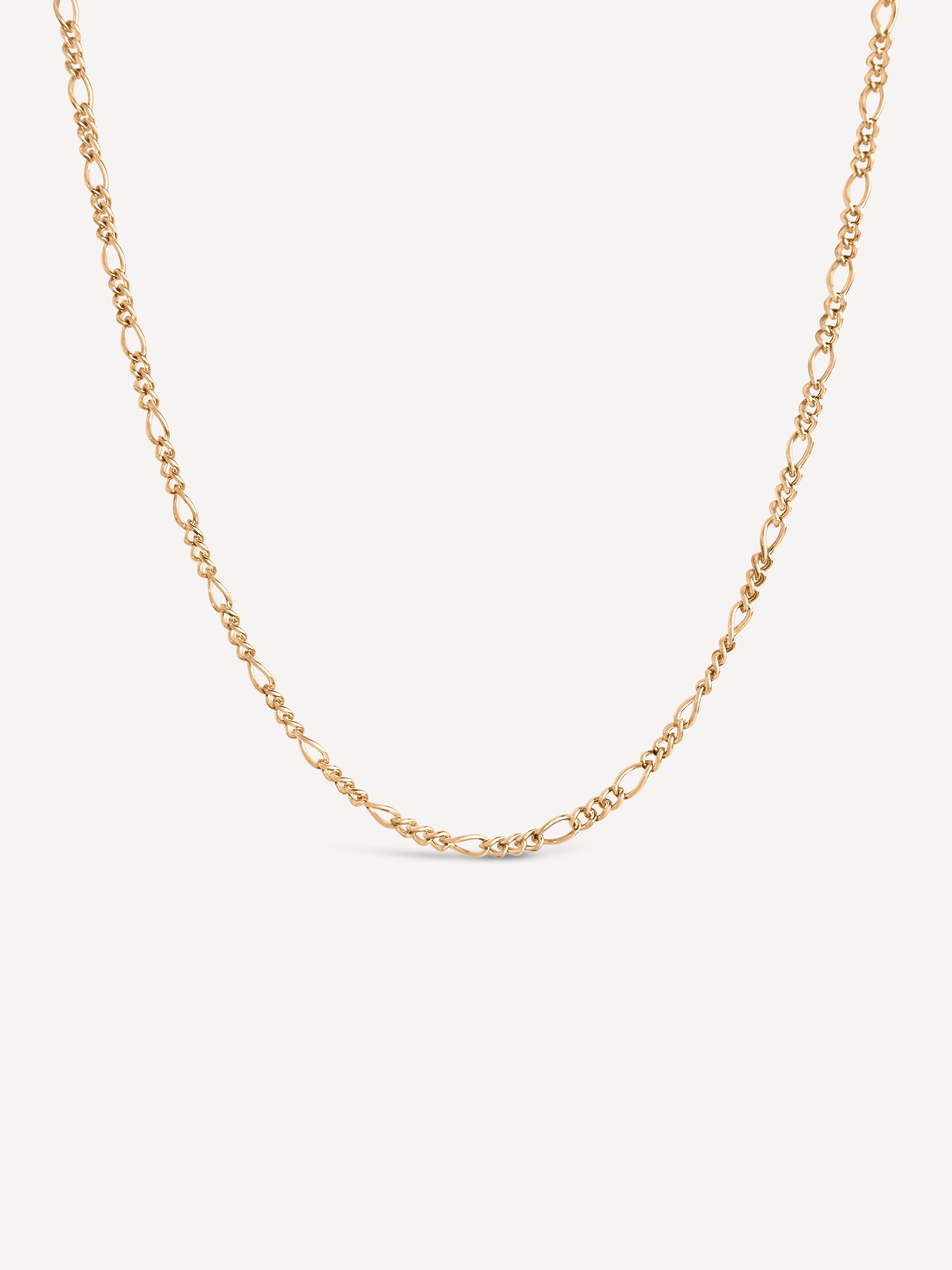 Gold chain necklace on a light beige background