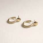 Gold hoop earrings on a light beige background