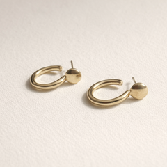 Gold hoop earrings on a light beige background