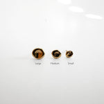 Multiple pairs of molten pebble stud earrings in 14k solid gold displayed on a clean surface.