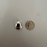 A small silver teardrop-shaped pendant with a reflective surface, shown next to a US quarter coin for scale on a light gray textured background.