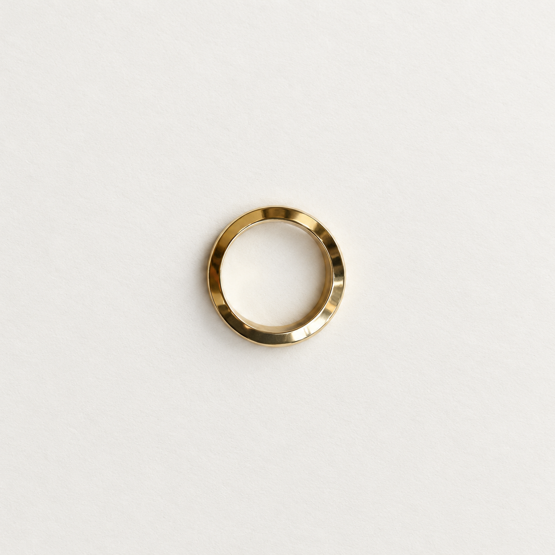 A minimalist gold band ring with a textured, hammered finish, centered on a clean white background.