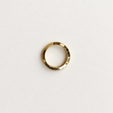 A minimalist gold band ring with a textured, hammered finish, centered on a clean white background.