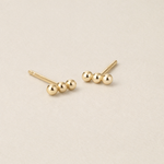 Pair of gold stud earrings on a beige background