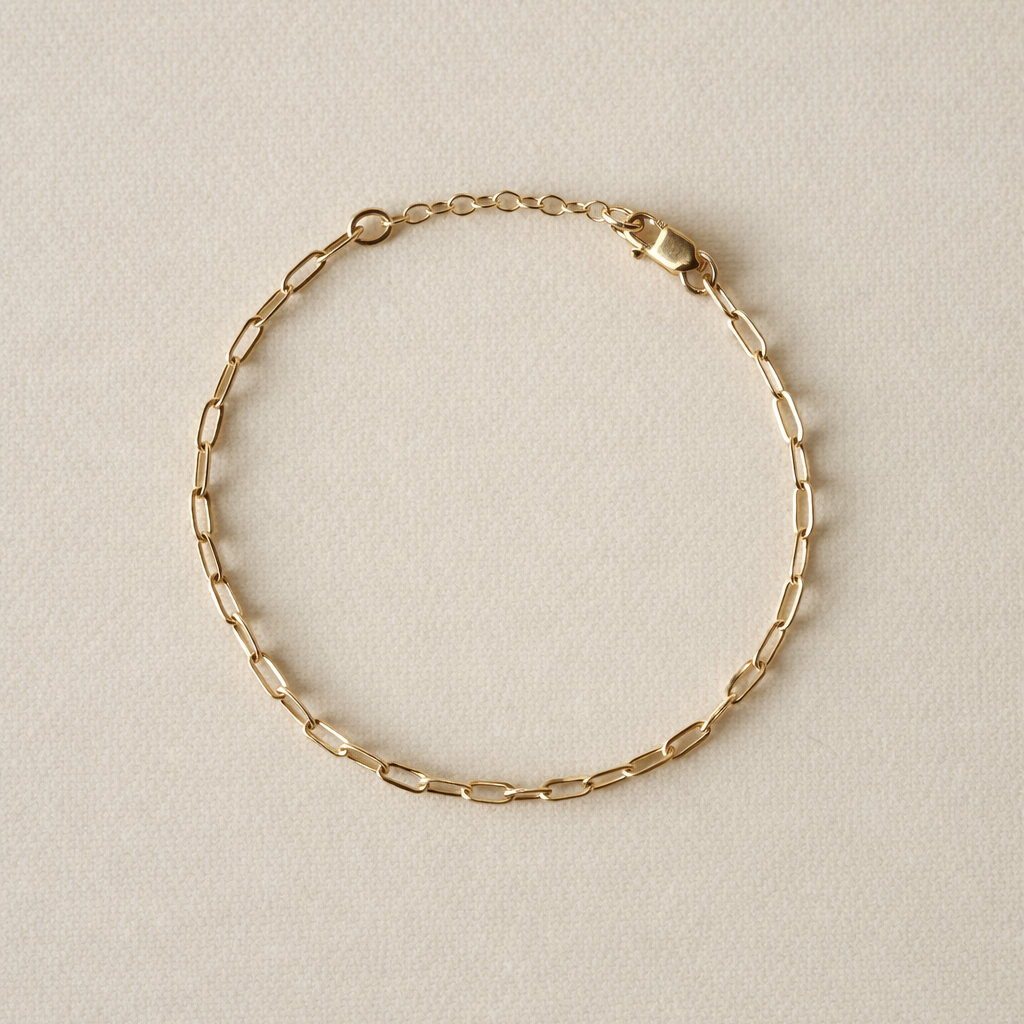Paperclip gold fill chain bracelet on a beige background with one inch extender