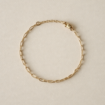 Paperclip gold fill chain bracelet on a beige background with one inch extender