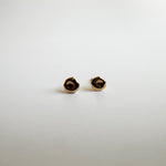 Close-up view of 14k solid gold molten pebble stud earrings showcasing their organic design.