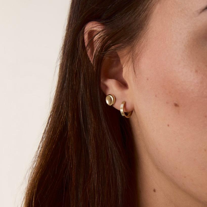 Woman wearing molten pebble stud earrings in 14k solid gold for a natural, elegant look.