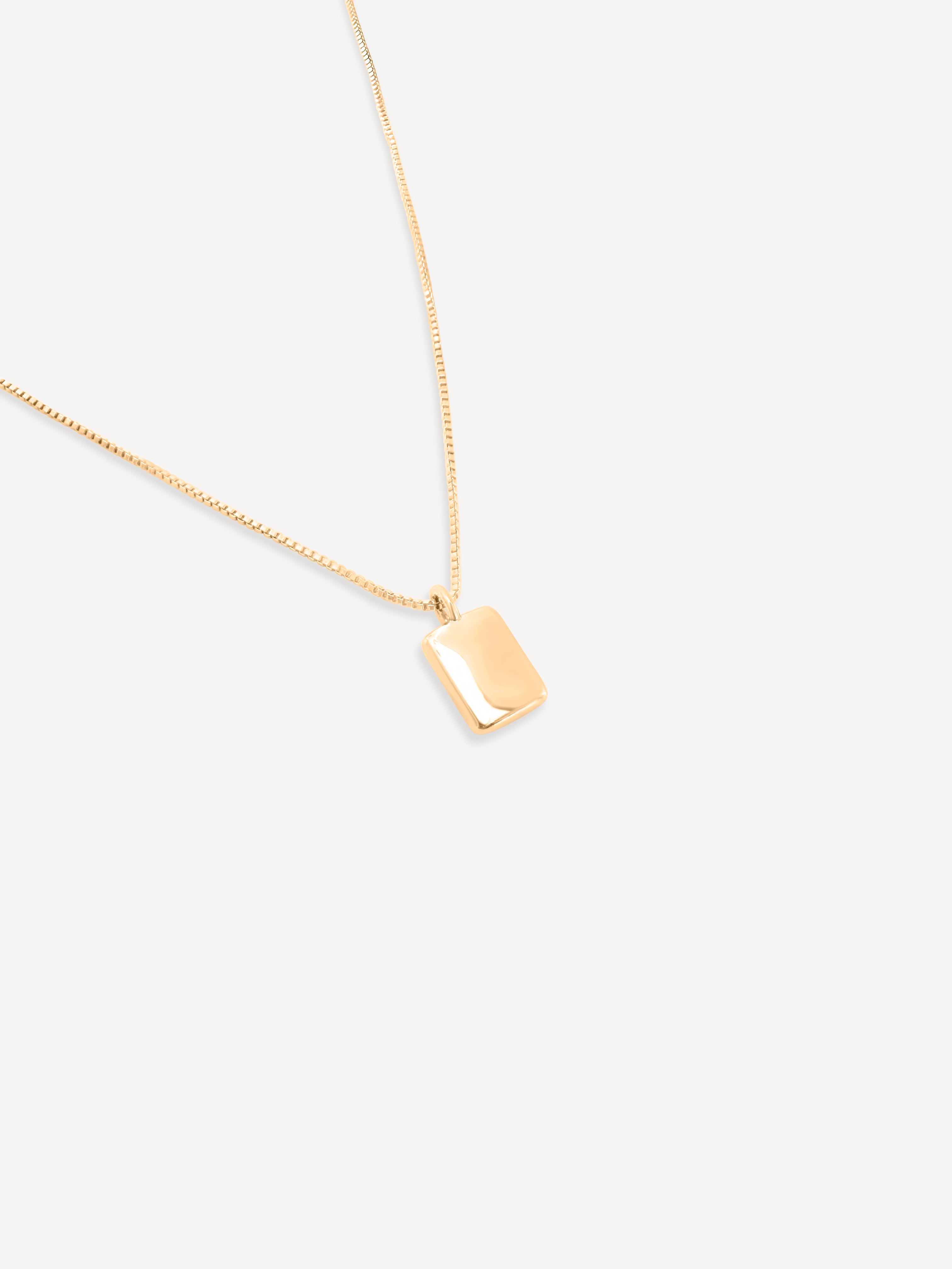 Full view of the gold chain necklace with the rectangular pendant displayed centrally against a white background.
