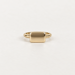 A minimalist gold signet ring with a flat, polished rectangular face, shown on a clean white background.