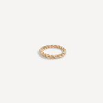 Gold ring with a twisted design on a light beige background