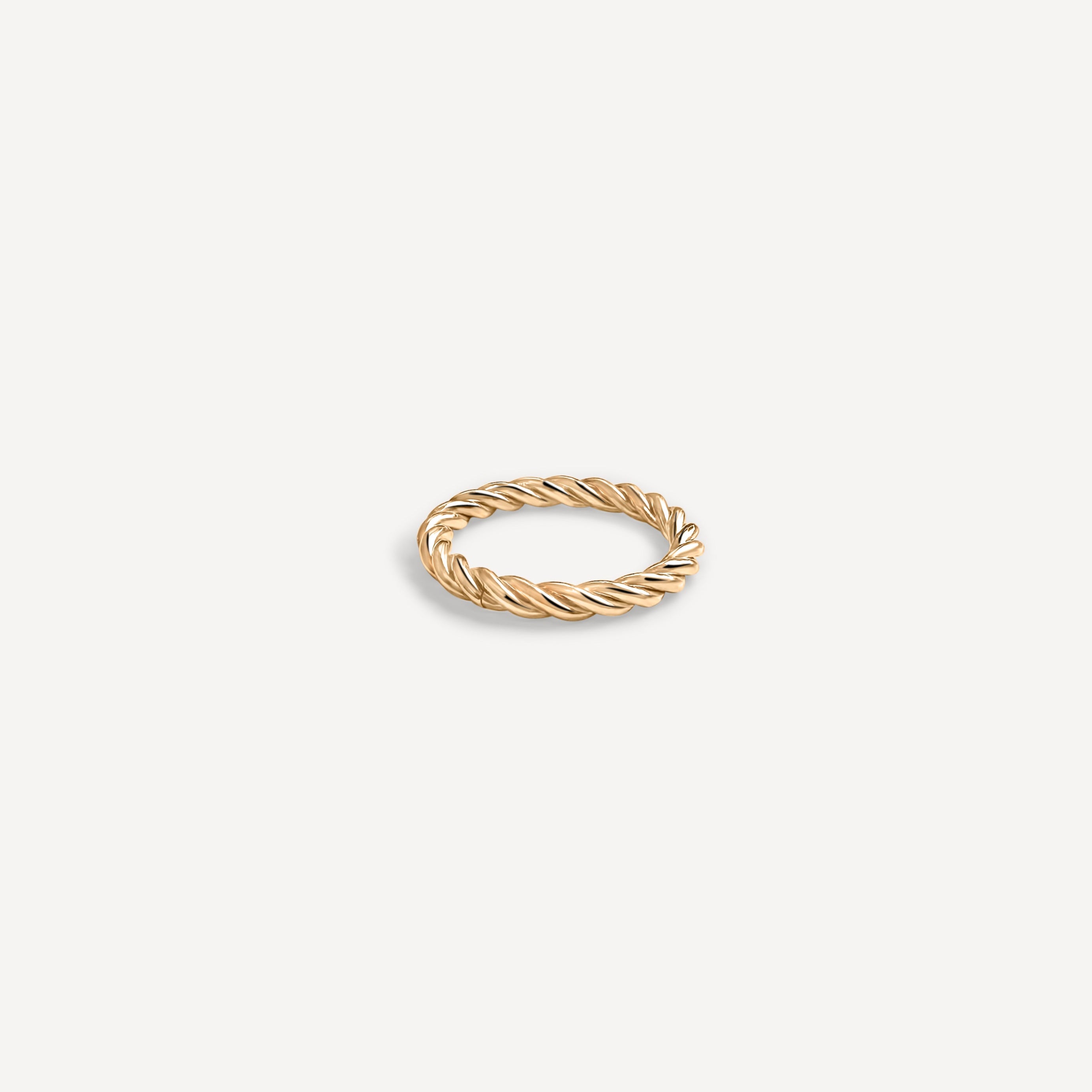 Gold ring with a twisted design on a light beige background