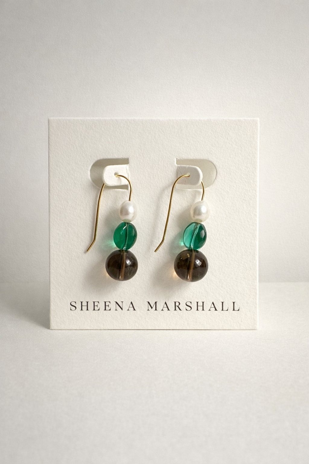 Pair of 14k gold fill glass and pearl earrings on a Sheena Marshall branded card against a light gray background