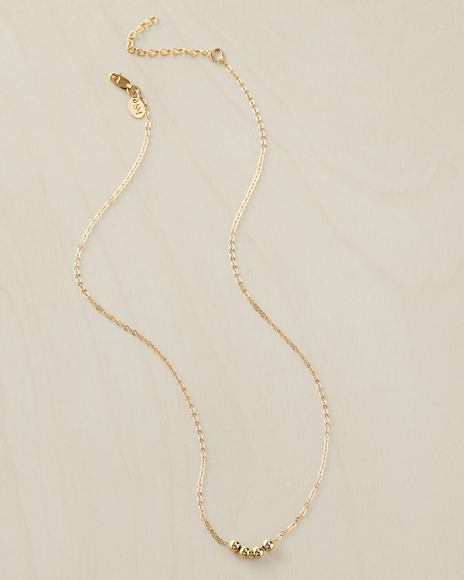 Add A Bead 14 Goldfill necklace on a beige background