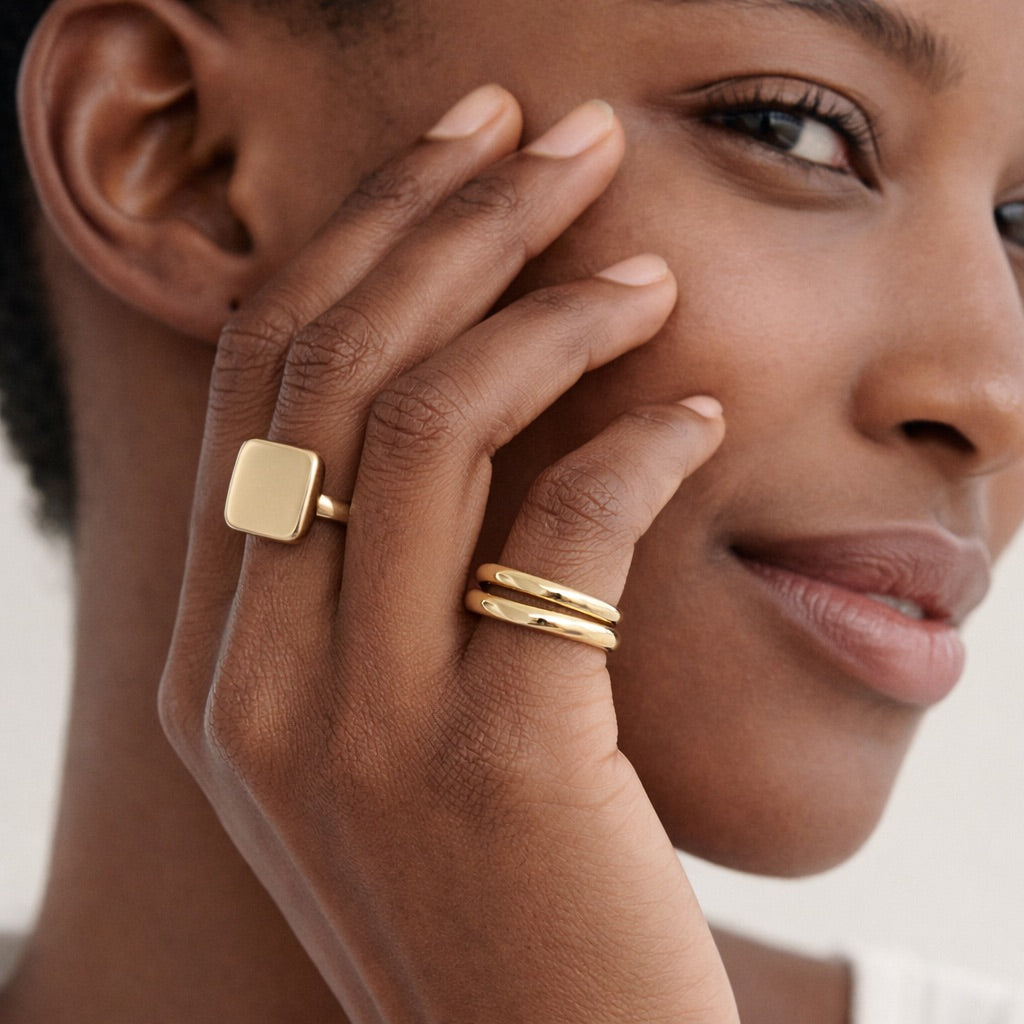 Model wearing a square signet ring and stacked gold bands