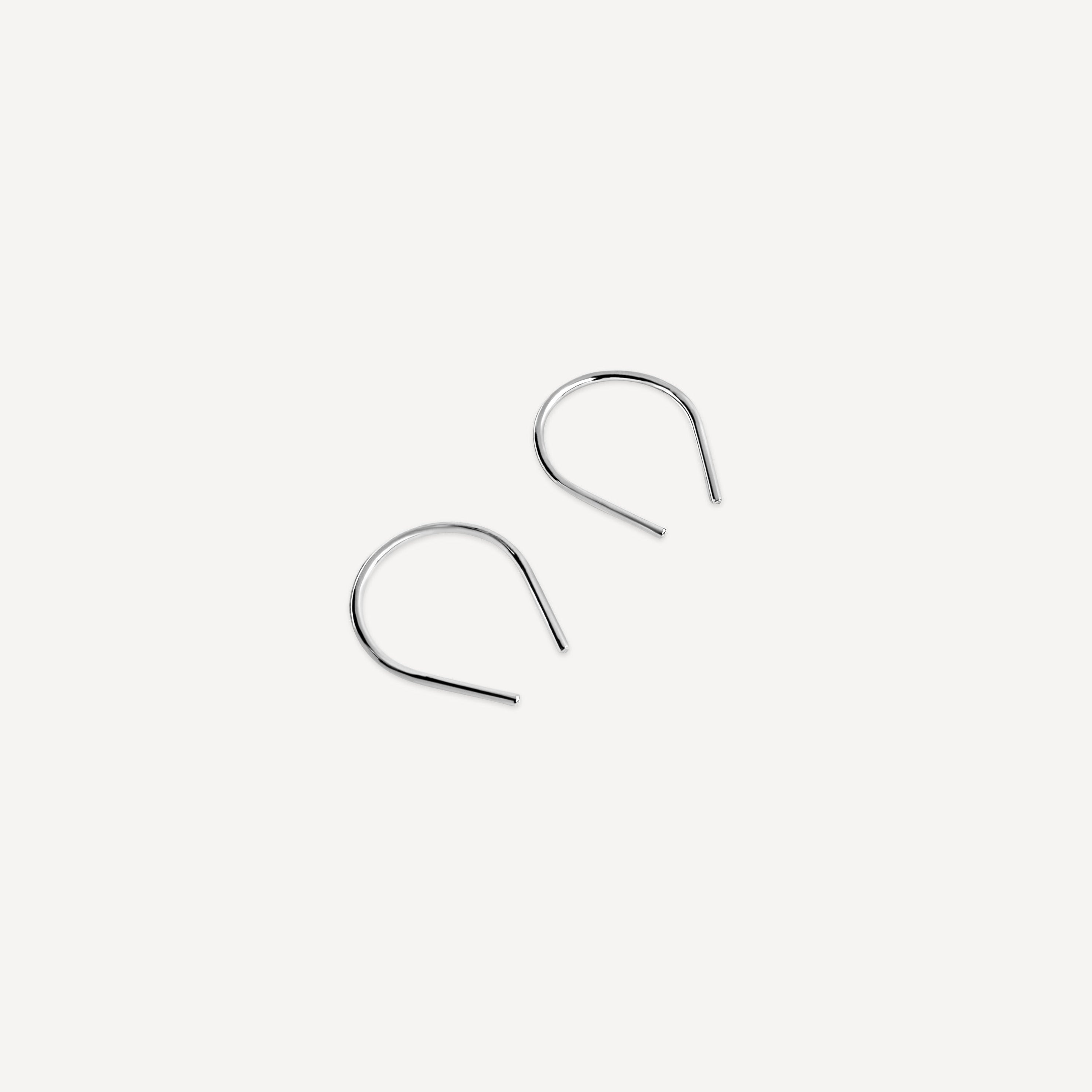 Minimalist sterling silver arch earrings displayed on a white background.