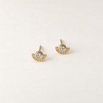 A pair of gold wing stud earrings with a clear round gemstone in the center, displayed on a clean, light off-white background.