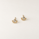A pair of gold wing stud earrings with a clear round gemstone in the center, displayed on a clean, light off-white background.