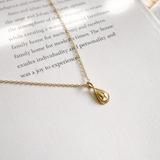 Gold necklace with a teardrop pendant on an open book