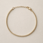Gold chain bracelet on a beige background