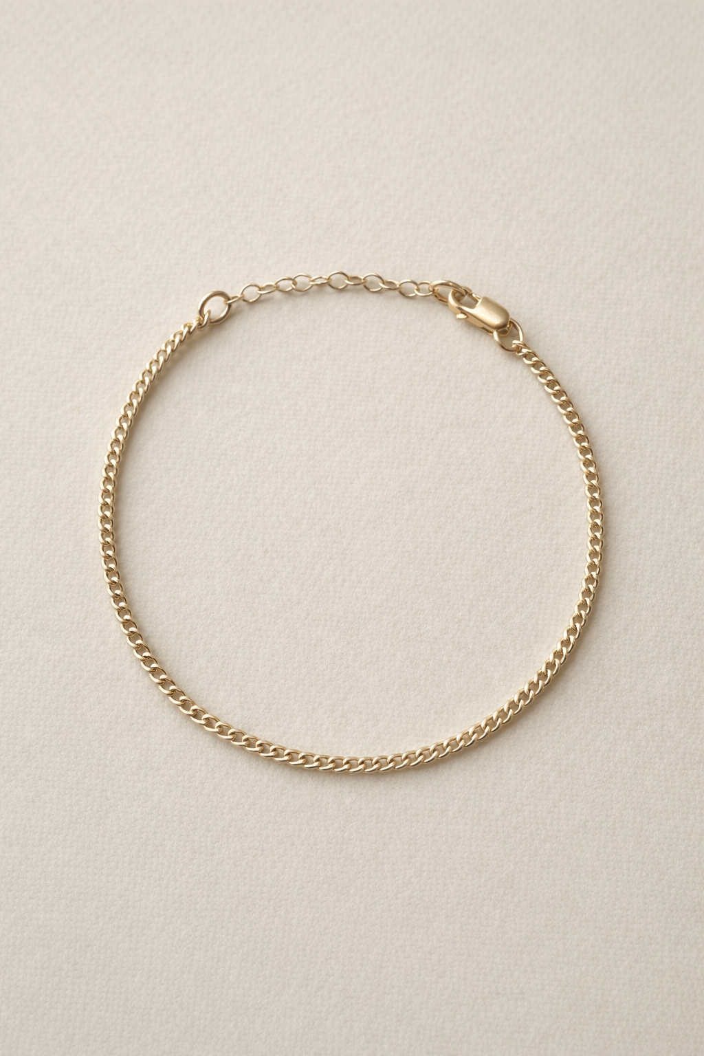 Gold chain bracelet on a beige background