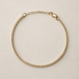 Gold chain bracelet on a beige background