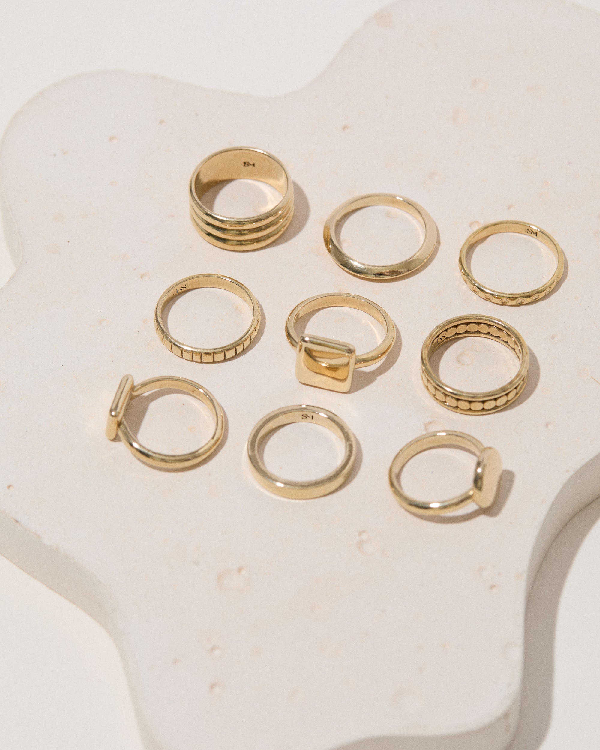 Group of brass rectangle rings arranged on a display, highlighting the minimalist design in various angles.