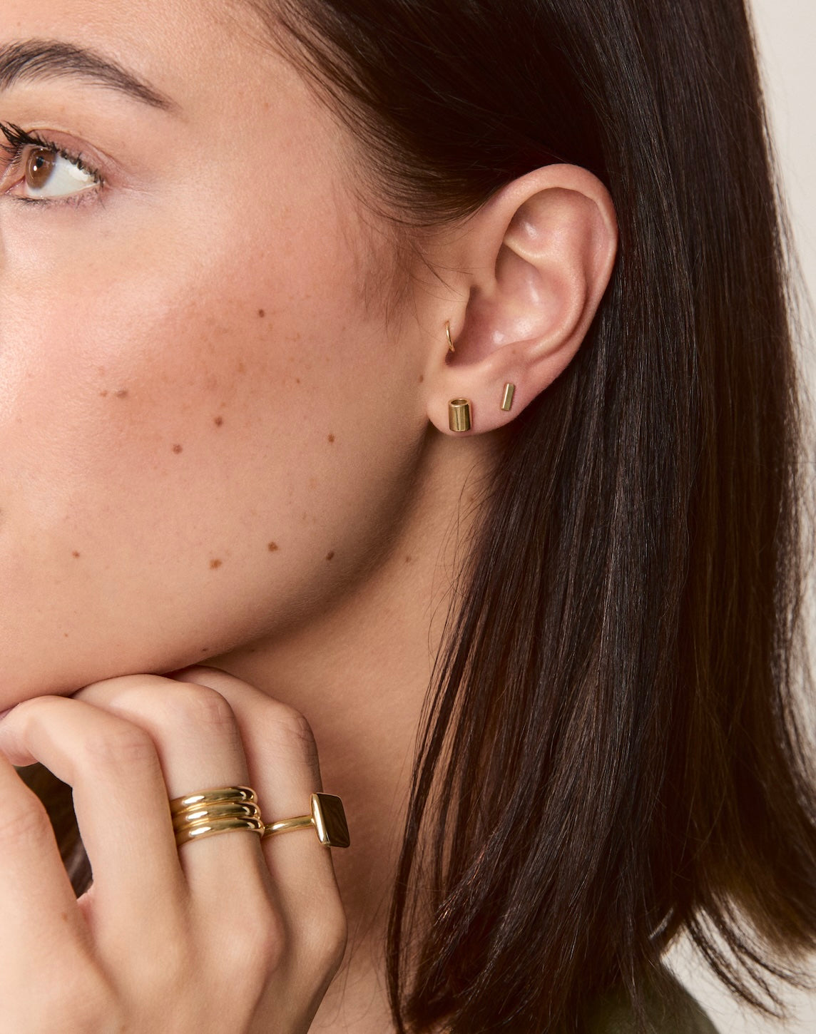 Model wearing solid gold flat bar studs for a minimal, modern look.