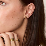 Model wearing solid gold flat bar studs for a minimal, modern look.