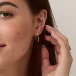 Model wearing Forma Rectangle Hoops in 14k solid gold, emphasizing their understated elegance and modern design.