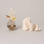 Furl Art Object, Bone displayed beside flowers